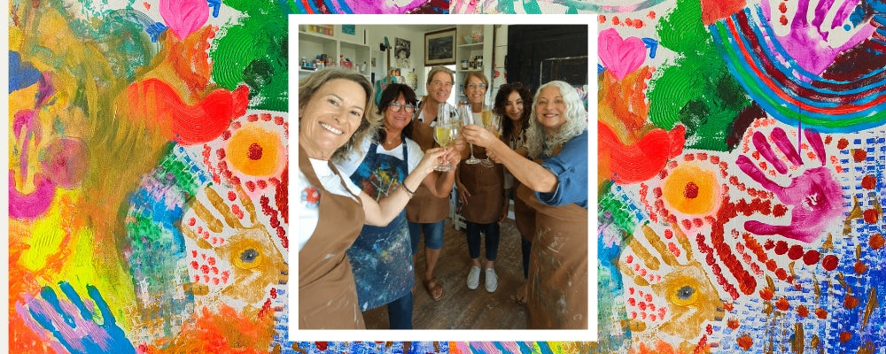 Five friends painting a canvas together during a birthday workshop in Ericeira