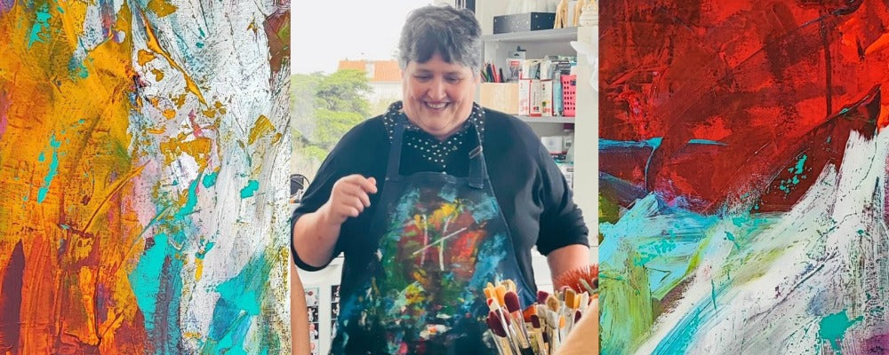 Mary smiling in the studio, between two paintings by Lenon B