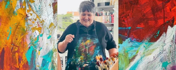 Lenon B laughing in her studio between two of her abstract paintings