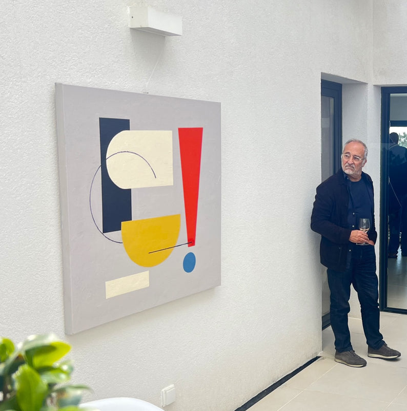 A visitor looking at a geometric painting by Lenon B in her studio in Ericeira